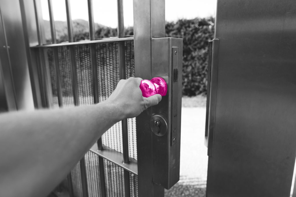 Image shows man extending their hand to the handle of electric outside door. The handle is coloured a bright pink to align with Fraser Dawbarns' colour scheme.