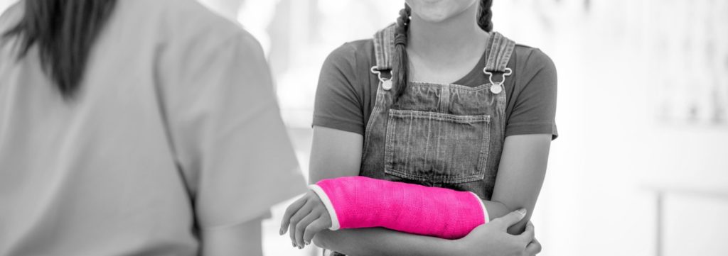 Image shows young girl at doctors office smiling to a nurse whose face is not visible. The girl wears plaits in her hair and is holding her arm which is in a cast. The cast is coloured bright pink to match the Fraser Dawbarns olour scheme.