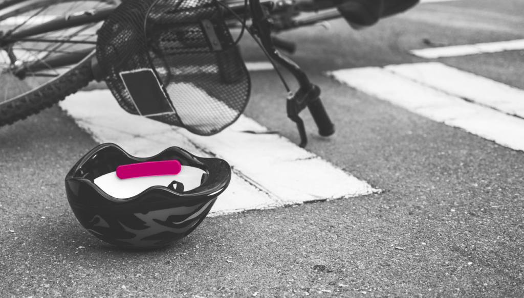 black and white photo of bike and helmet laying in the road after an accident