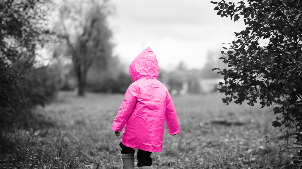 child in a raincoat walking in a field